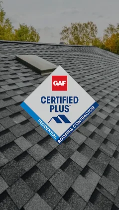 A close-up of a gray shingle roof with a skylight, overlaid with a GAF Certified Plus Residential Roofing Contractor badge. Trees are visible in the background—a showcase of Prime Roofing and Restoration’s top roofing services in Georgia.