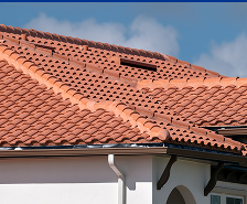A close-up view of a house roof covered with red clay tiles, featuring multiple slopes, under a clear blue Georgia sky—showcasing the quality work provided by Prime Roofing and Restoration.