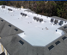 A large building in Georgia with a white flat roof featuring multiple HVAC units and vent pipes; surrounding areas have trees, and the sloped sections of the roof have skylights—ideal for Prime Roofing and Restoration services.